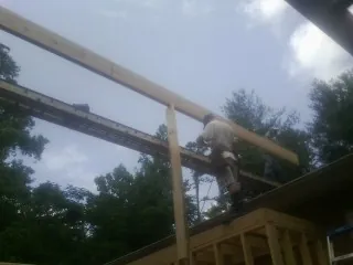 Carpenter setting a ridge beam over a new addition frame — Ice Dam Removal by Roofing Brothers in Robards