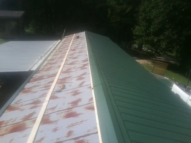 Old rusted panels beside newly installed green metal roofing — Wind Damage Roof Repair by Roofing Brothers in Robards
