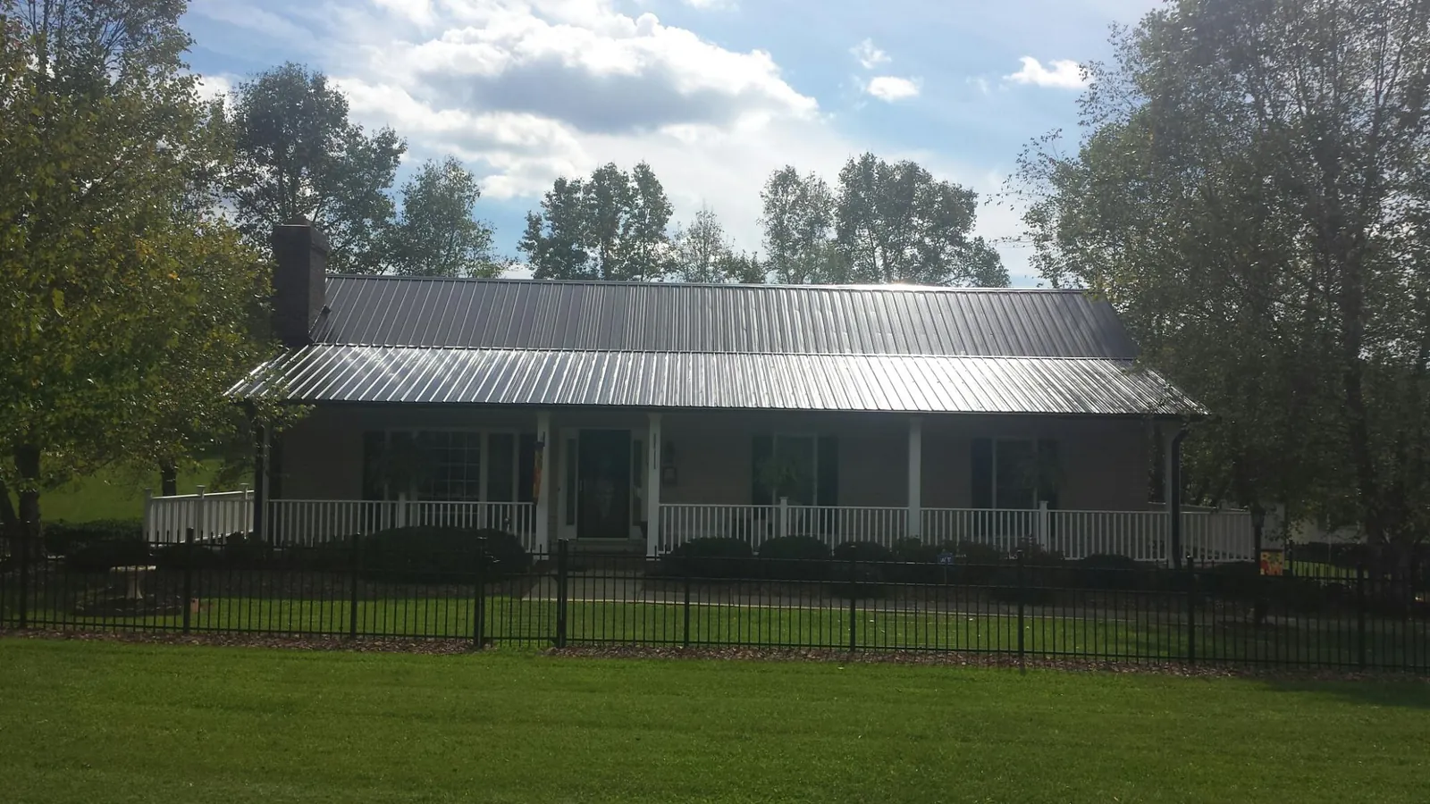 Gray metal roof on a brick ranch with a full width front porch — Gutter Guard Installation work by our crew in Robards